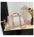 Pink and white canvas tote bag with adjustable wide strap shown in stylish indoor setting - Pink