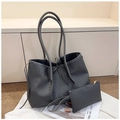Detail der grauen Flecht-Tote Bag und passenden Clutch vor minimalistischem Hintergrund - Grau