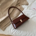 Bolso baguette minimalista marrón oscuro con hebilla dorada sobre tela blanca y abrigo - Marrón Oscuro