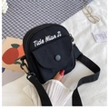 Close-up of black canvas crossbody bag with adjustable strap and front pocket detail - Black