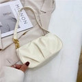 Bolso de hombro plisado color crema con cadena dorada en un escenario de moda - Blanco