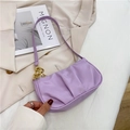 Bolso baguette plisado morado con cadena dorada sobre fondo de chaqueta blazer beige - Morado