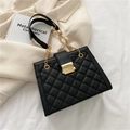 Modern black quilted tote bag with gold chain strap on white fabric background - Black