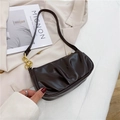 Dark brown pleated baguette shoulder bag with gold chain strap in a fashion setting - Brown