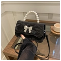 Close-up of black pleated bag featuring pearl handle and silver metal bow detail - Black