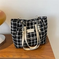 Detalle de bolso tote de tweed a cuadros con colgante de perlas y cadena en mesa madera - Negro