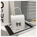 Detalle de mini bolso de cuero blanco con hebilla de lazo metálico plateado en revista - Blanco