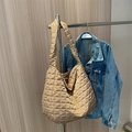 Grande borsa shopper trapuntata beige in stile puffer appesa su sfondo casual - Cachi