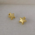 Minimalistische mattgoldene Stern-Ohrstecker mit gebürstetem Finish auf neutralem Stoff - Gebürstetes Gold