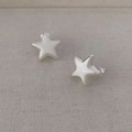 Minimalistische matte silberne Sternstecker auf beigem Stoff mit klaren Kunststoffsteckern - Gebürstetes Silber