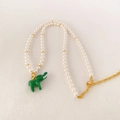 Detalle de collar de perlas con colgante de elefante en esmalte verde y cierres dorados - Blanco