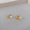 Close-up of polished gold bead and elegant white pearl earrings on soft fabric - Gold