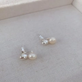 Minimalist 925 silver stud earrings with high-luster white pearls on a beige texture - Silver