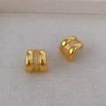 Elegant gold C-shaped hoop earrings with micro-inlaid cubic zirconia stones on beige fabric - Gold