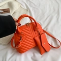 Dettaglio della borsa trapuntata arancione e pochette su fondo in tessuto bianco - Arancione