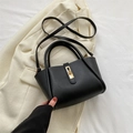 Elegante zwarte crossbodytas met gouden sluiting op een lichte blazer - Zwart