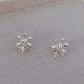Boucles d'oreilles fleurs en argent avec perles mates sur fond de lin beige - Perle Blanche