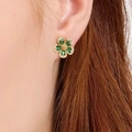 Eleganti orecchini a fiore con pietre verdi e centro dorato, indossati sull'orecchio - Verde