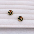 Macro view of vintage gold-plated twisted knot earrings with green enamel inlay details - Black
