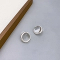 Minimalistische zilveren oorknopjes met witte kristallen op een grijze getextureerde achtergrond - Stud oorbellen