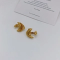 Macro shot of gold crescent moon earrings with irregular textured surface on white background - Gold