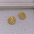 Vue détaillée des boucles d'oreilles ovales dorées ajourées sur tissu blanc texturé - Stud boucles d'oreilles / Doré