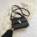 Classic black trapezoid crossbody bag with gold leaf-shaped twist lock on beige fabric - Black