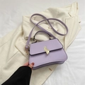 Lavender purple leather crossbody bag with gold wave buckle on beige blazer jacket - Purple