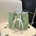Light green pleated tote bag with pearl chain and fashion label on a white chair - Green
