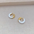 Détail de boucles d'oreilles créoles dorées avec émail blanc et texture polie - Blanc