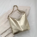 Borsa tote dorata metallizzata lucida di grande capacità esposta su un blazer beige - Oro