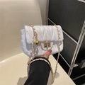 White quilted crossbody bag with gold chain strap and spherical buckle held in hand - White