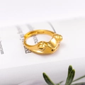 Verstellbarer goldener Froschring mit markanten Augen auf einem weißen Buch liegend - Geschlossene Augen Stil / Gold