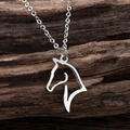 Minimalist hollow horse head pendant necklace in stainless steel on dark wood background - Silver