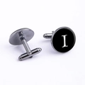 Macro shot of gunmetal cufflink featuring a black disc with a white serif letter I - Letter I
