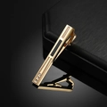 Men's gold tie clip with black enamel inlay and three crystals on a dark surface - Gold