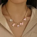 Close-up of gold multi-pendant necklace with pink enamel charms on model neck - Wings Bow Style