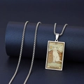 Detalle del collar de tarot de gato plateado sobre un soporte cilíndrico azul marino - LA TEMPLANZA