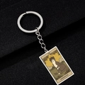 Macro shot of Strength Tarot card cat illustration on a rectangular metal keychain - Strength