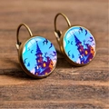 Macro detail of Halloween alloy hook earrings with spooky castle and bat glass dome art - Spire Castle & Bats with Bright Blue Background (Style-16)
