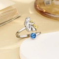 Detail eines silbernen Rings mit Mädchen das einen goldenen Hund hält und blauem Stein - Legierungsringe Im Dezember / Einstellbar Offen
