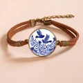 Macro detail of retro bronze bracelet with blue porcelain bird gem and brown cord - Blue and White Bird Style 3 (款式3)