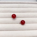 Klassische 10mm rote Achat-Ohrstecker mit Silberstiften auf einer beigen Schmuckablage - Rot