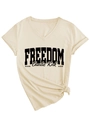 Dettaglio della maglietta crema con scollo a V, scritta Freedom e nodo decorativo - S / Sabbia