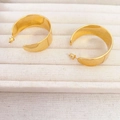 Dettaglio di orecchini a cerchio a C dorati larghi con finitura lucida a specchio - Oro