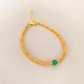 Detail of beaded bracelet with orange faceted beads and a green centerpiece stone - Green Agate