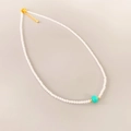 Détail du collier de perles blanches translucides avec une perle d'accent turquoise - Collier Amazonite