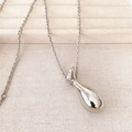 Polished silver teardrop necklace pendant on textured fabric for layered look - Silver