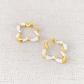 Dettaglio degli orecchini a quadrifoglio placcati oro con smalto bianco su tessuto strutturato - Motivo Floreale Bianco