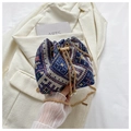 Detalle de bolso saco tejido con patrones geométricos, cadena dorada y perlas - Azul